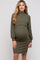 woman wearing a dark green ribbed maternity dress with a mock neck and long sleeves, showing her baby bump