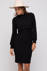woman wearing a black ribbed long sleeve dress with a mock neck and puffed sleeves, accessorized with a wide-brim hat