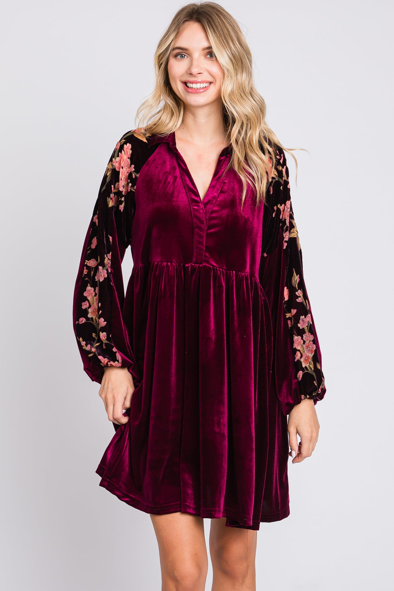woman wearing a burgundy velvet dress with floral long sleeves and a v-neckline