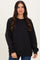 woman wearing a black oversized sweatshirt with ribbed cuffs and hem, posing against a neutral background