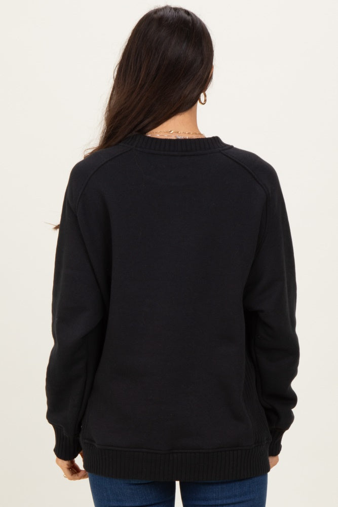 woman wearing a black oversized sweatshirt, shown from the back, with ribbed cuffs and hem