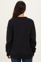 woman wearing a black oversized sweatshirt, shown from the back, with ribbed cuffs and hem
