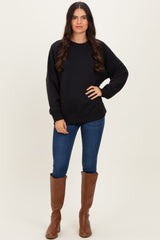 woman wearing a black oversized sweatshirt with long sleeves and blue skinny jeans paired with brown knee-high boots