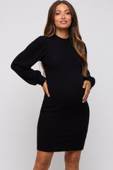 woman wearing a black ribbed long sleeve maternity dress and holding her baby bump