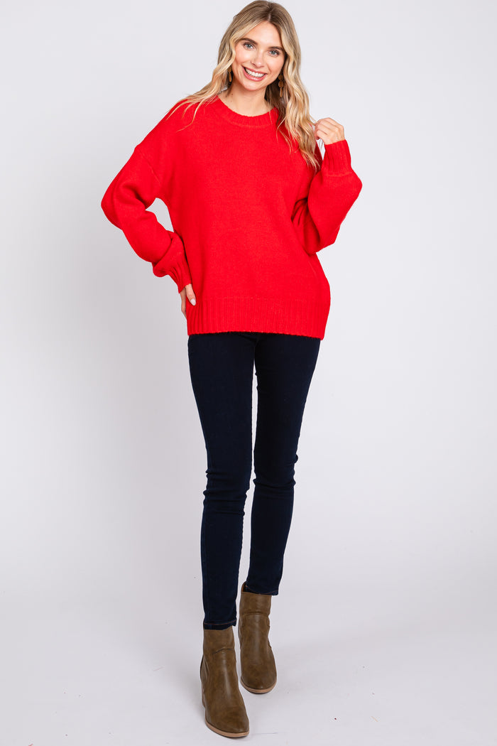 woman wearing a bright red oversized sweater paired with dark skinny jeans and ankle boots