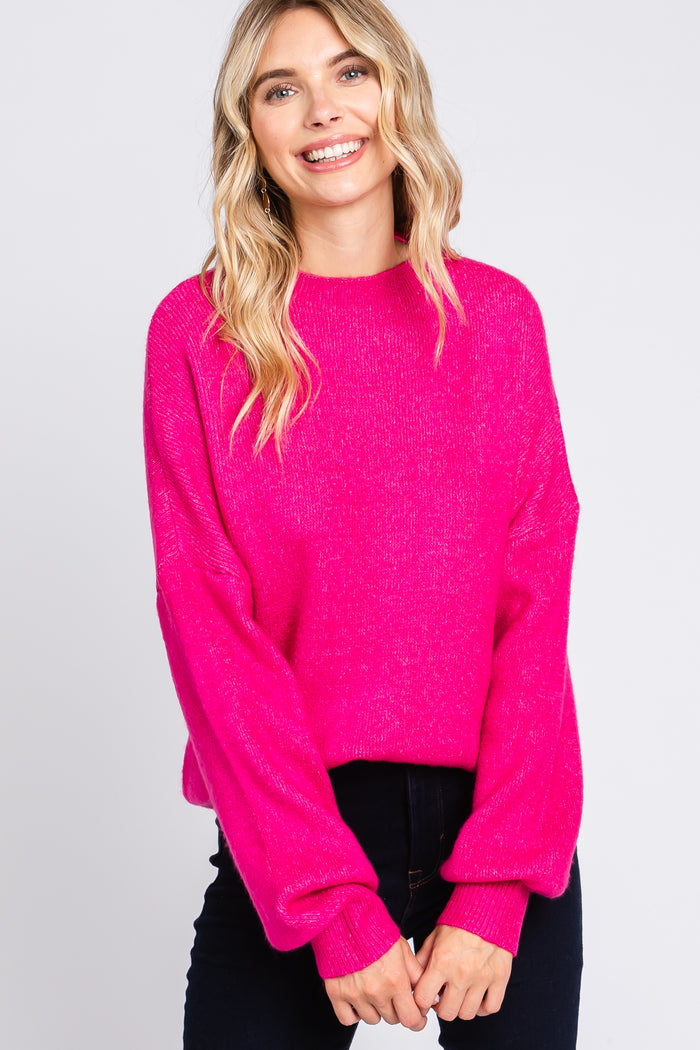 woman wearing a bright pink oversized sweater with balloon sleeves and a relaxed fit