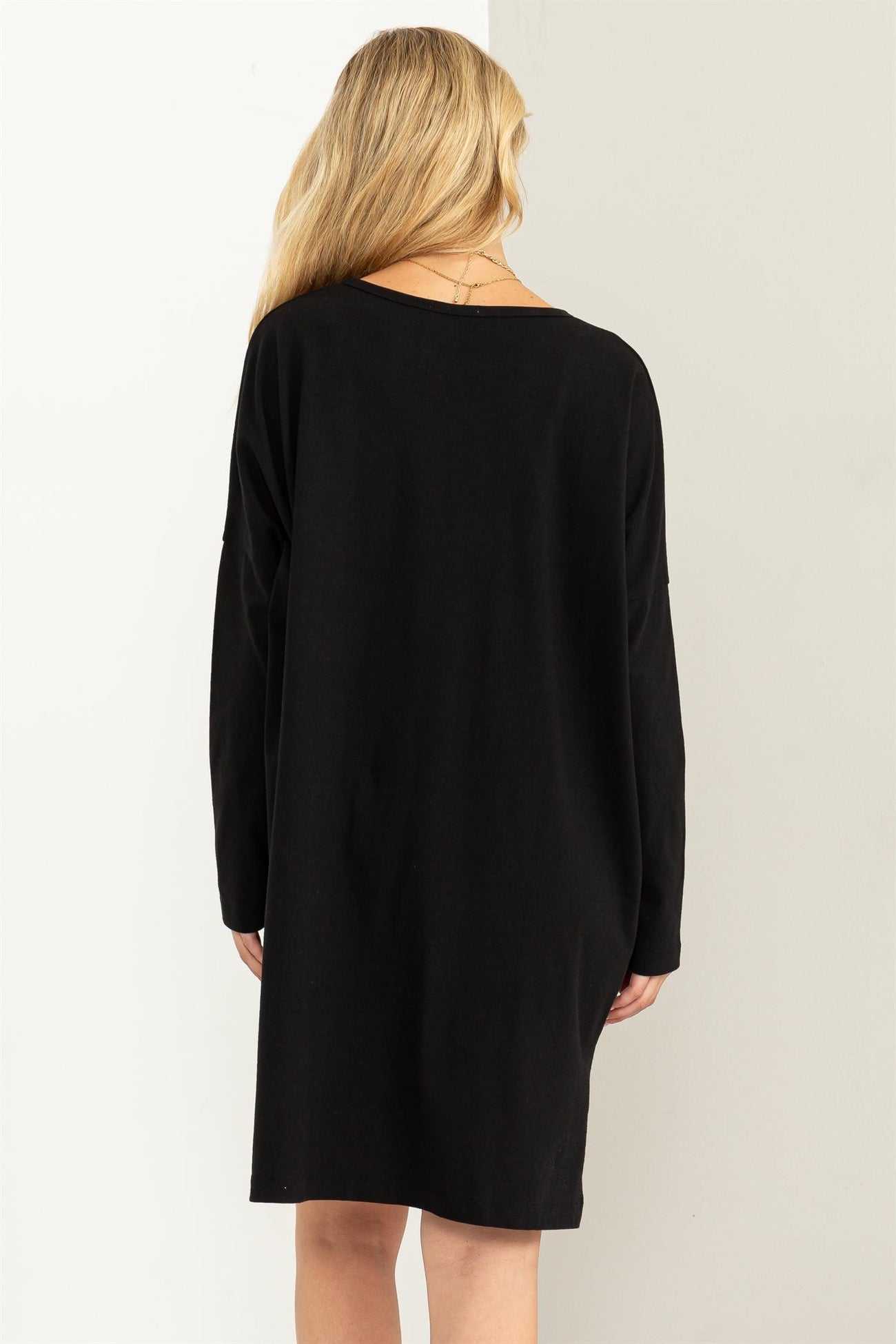 woman wearing a black long sleeve oversized dress, viewed from the back
