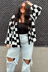 woman wearing a black and white checkered cardigan over a black top and distressed light blue jeans