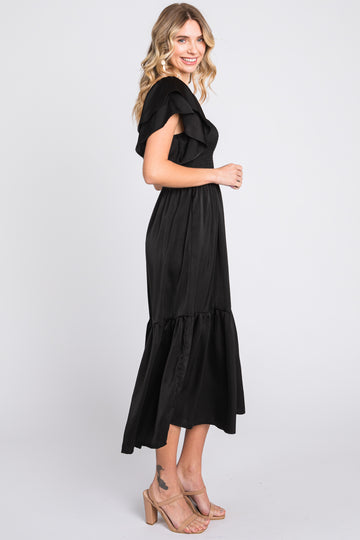woman wearing a black off-the-shoulder maxi dress with ruffle details and a tiered skirt