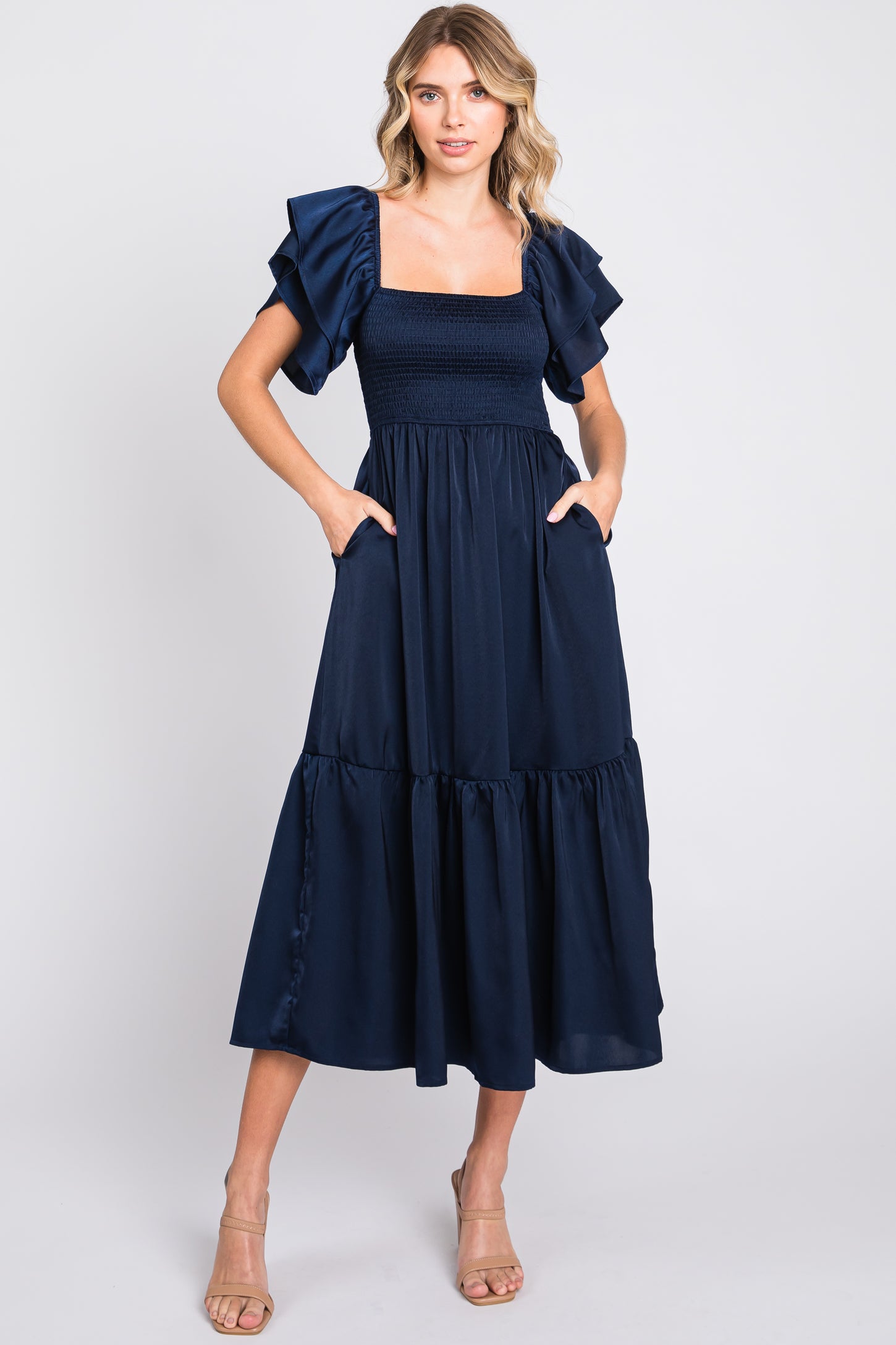 woman wearing a navy blue maxi dress with ruffle sleeves and pockets, styled with a fitted bodice and tiered skirt