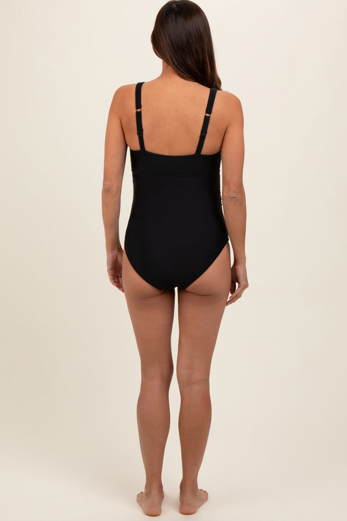 woman wearing a black maternity swimsuit, viewed from the back, featuring adjustable straps