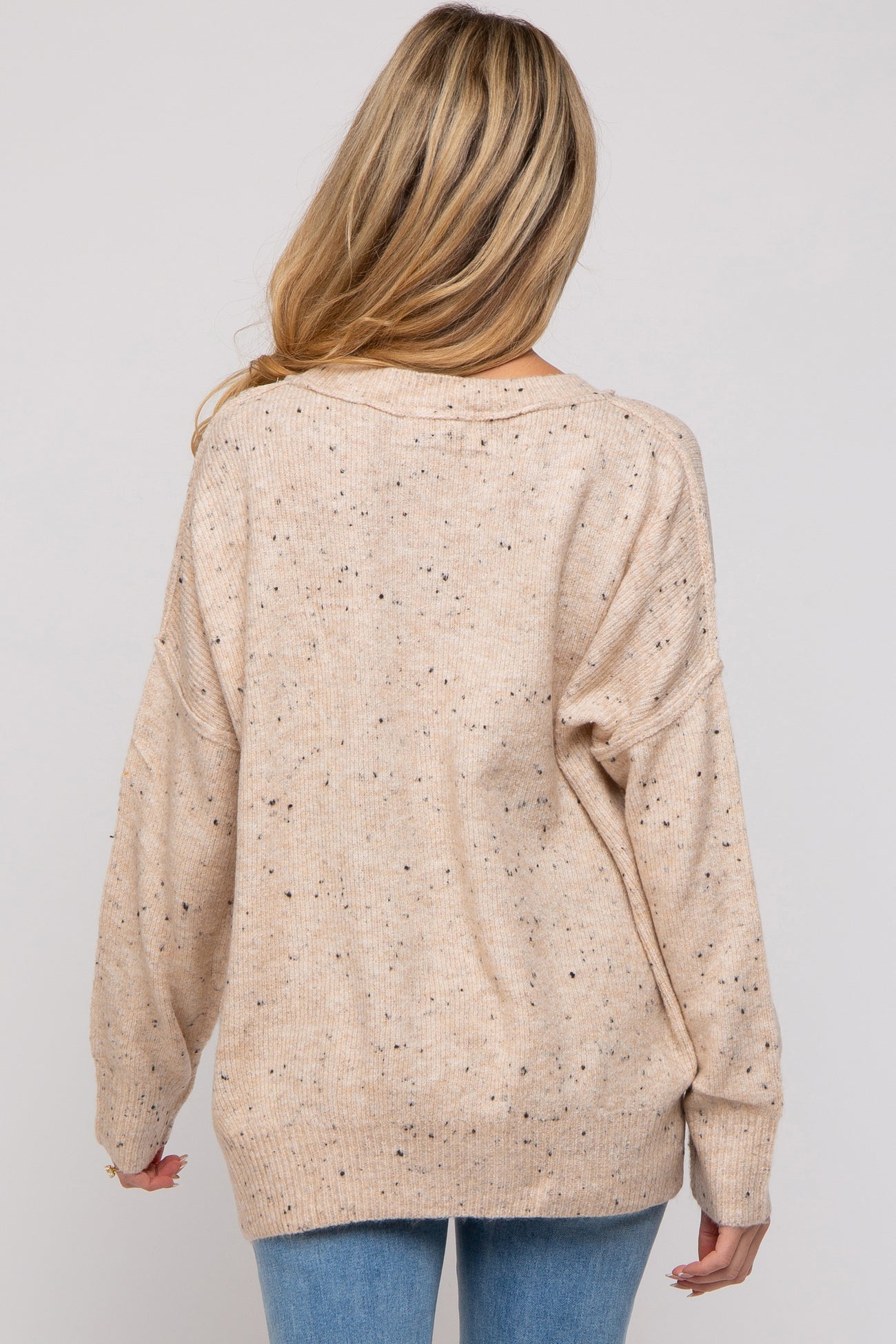 woman wearing a beige maternity sweater with a relaxed fit and speckled detailing, viewed from the back