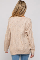 woman wearing a beige maternity sweater with a relaxed fit and speckled detailing, viewed from the back
