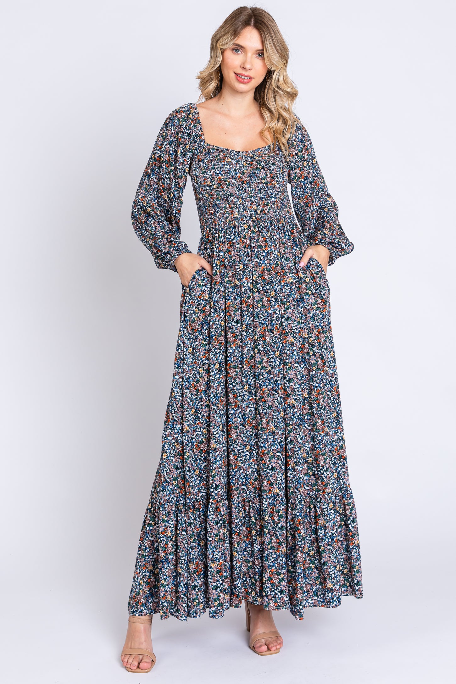 woman wearing a long floral maxi dress with puff sleeves and a square neckline, featuring side pockets