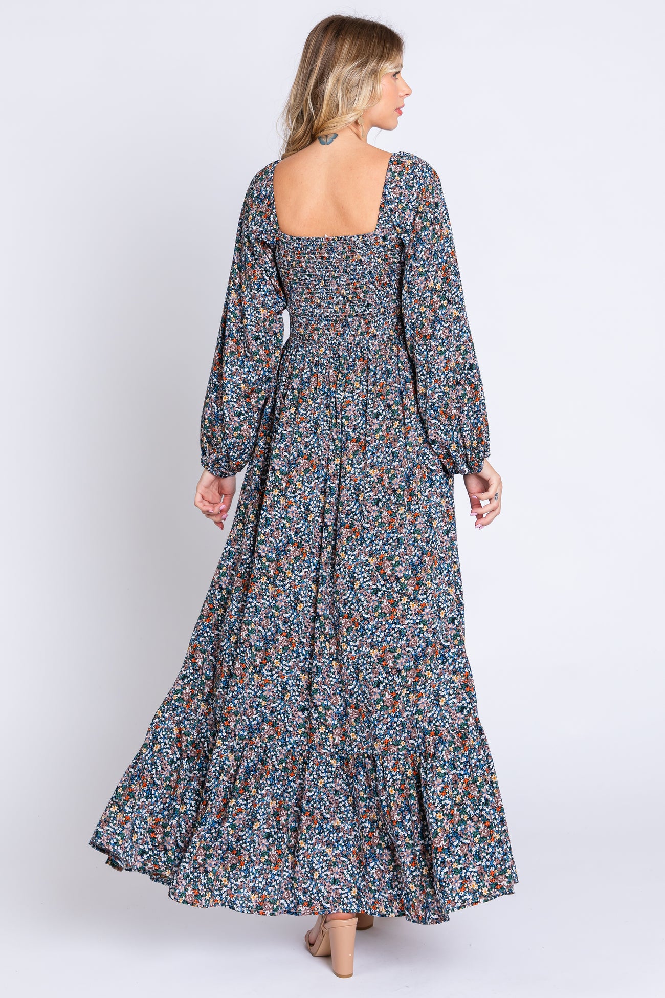 woman wearing a long floral maxi dress with a square neckline and long puff sleeves, showing the back view