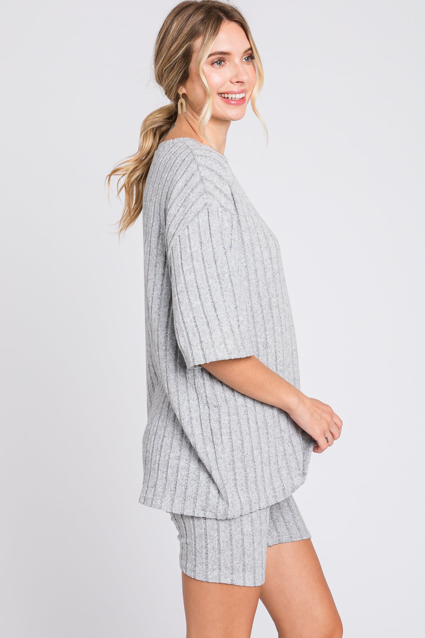 woman wearing a gray ribbed oversized t-shirt and matching shorts, smiling and posed sideways
