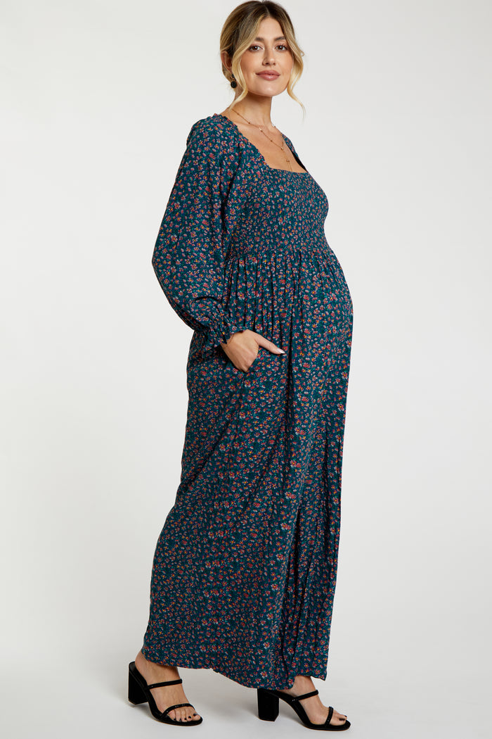 woman wearing a navy floral maternity maxi dress with long sleeves and pockets, showcasing her baby bump