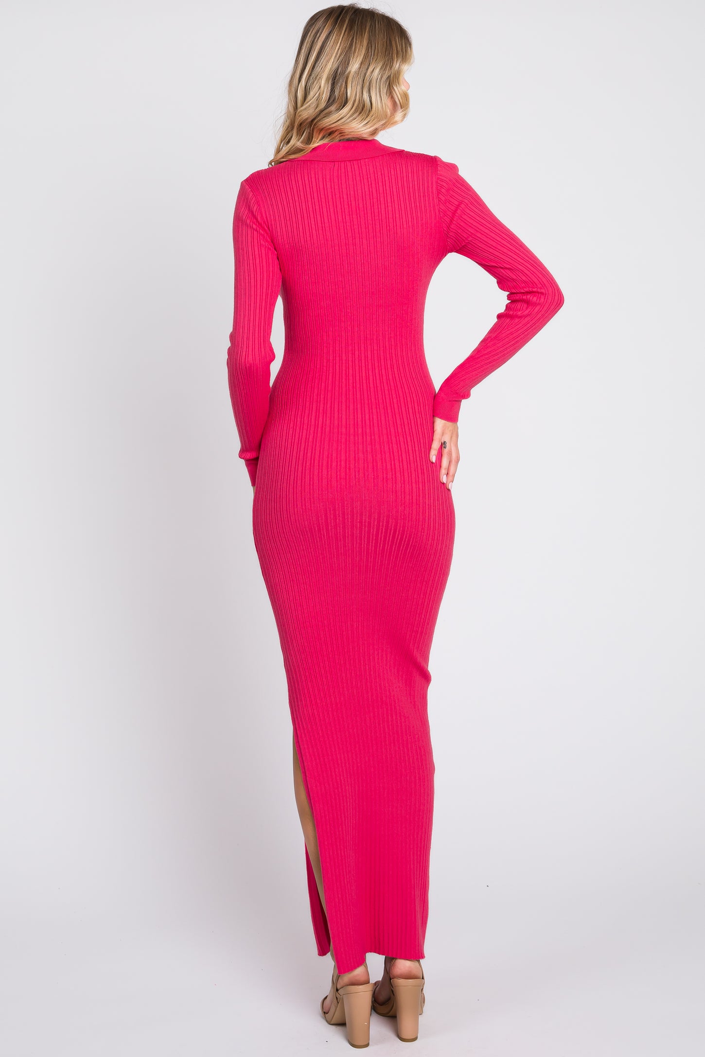 woman wearing a hot pink ribbed maxi dress with long sleeves and side slit, viewed from the back
