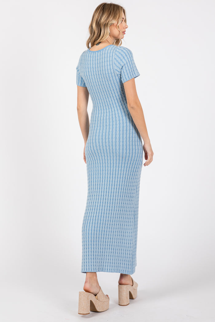 woman wearing a light blue ribbed maxi dress with short sleeves and a fitted silhouette, standing with her back to the camera