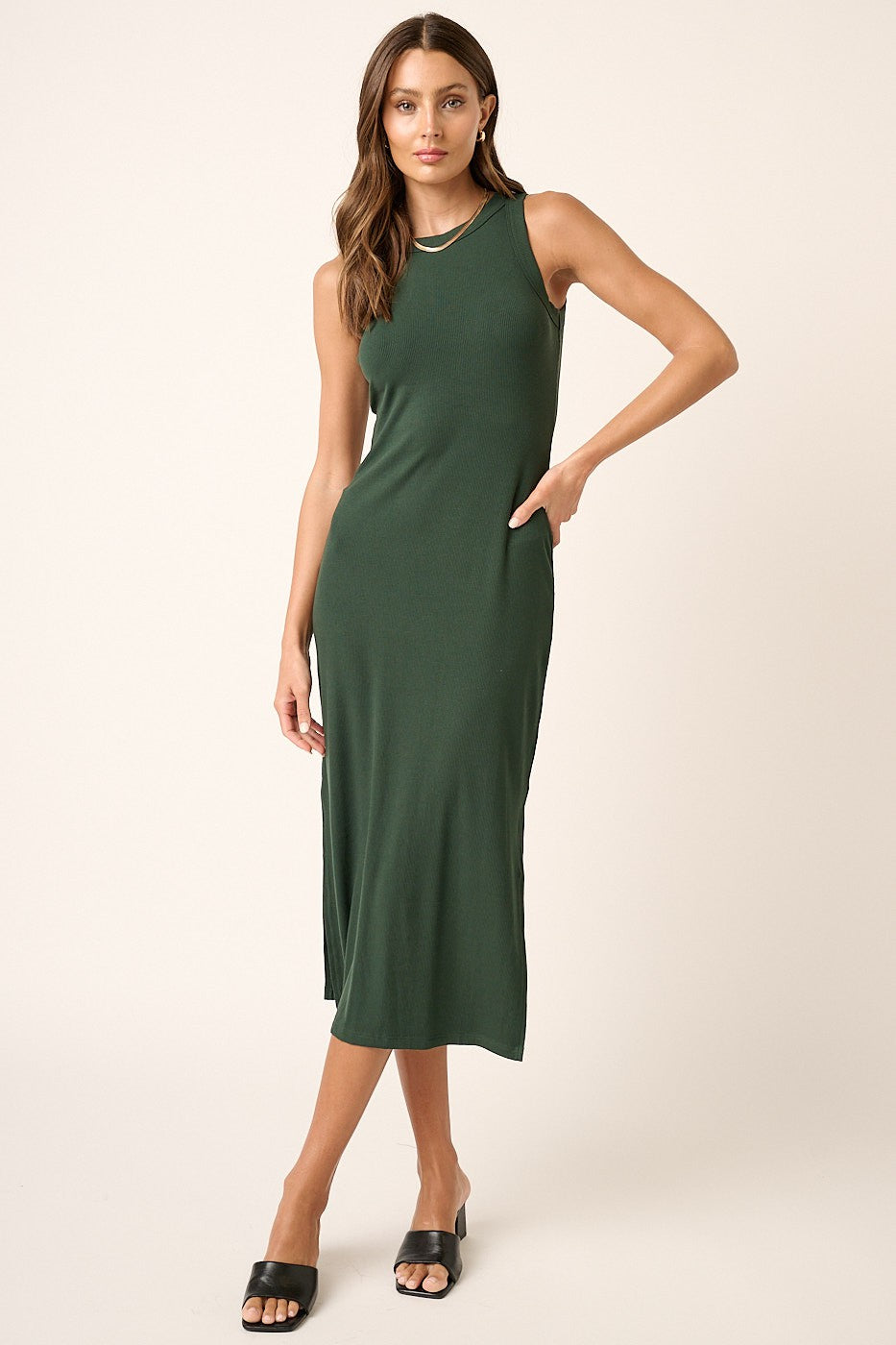 woman wearing a dark green sleeveless midi dress with side pockets and a relaxed fit