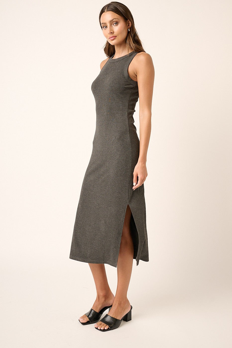 woman wearing a gray sleeveless midi dress with side slits and styled with black heeled sandals