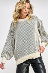 woman wearing a cream striped oversized knit sweater with balloon sleeves and a relaxed fit, paired with black leather pants