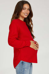 woman wearing a red knitted maternity sweater and holding her baby bump