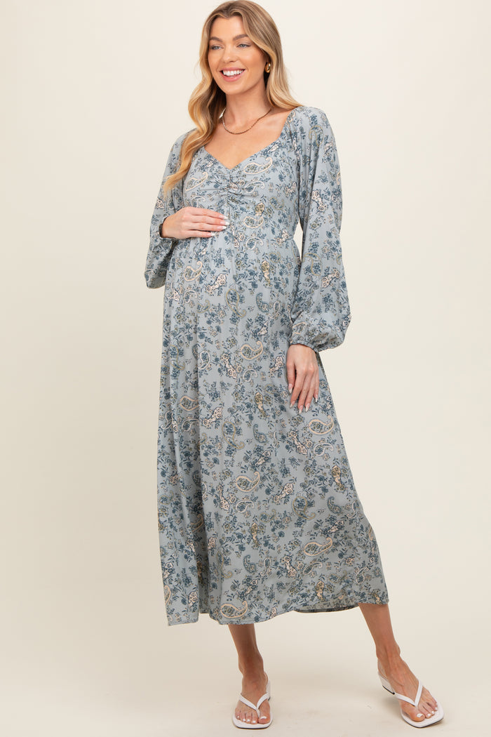 woman wearing a blue floral maternity dress with long sleeves and a baby bump visible