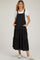 woman wearing a black maternity dress with a tiered design, buttons, and side pockets, styled with a white t-shirt and sneakers