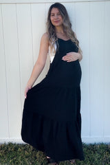 woman wearing a black tiered maternity maxi dress and holding her baby bump