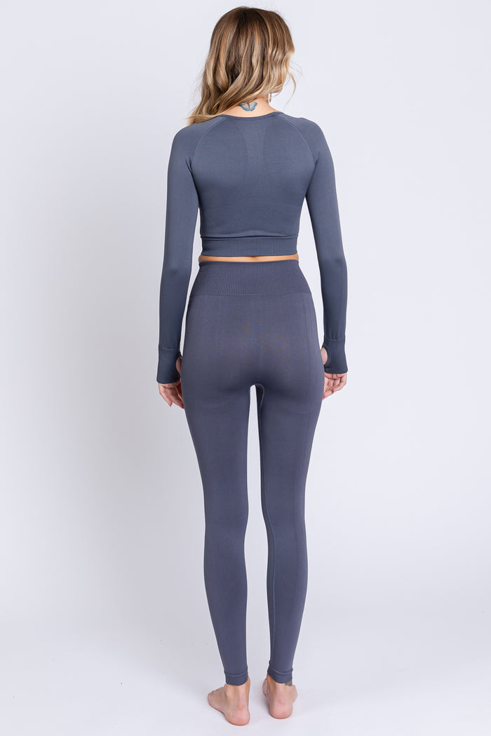 woman wearing a gray long sleeve crop top and matching high-waisted leggings, viewed from the back