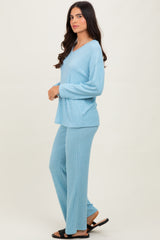 woman wearing a light blue ribbed loungewear set with a loose top and matching pants, standing in profile