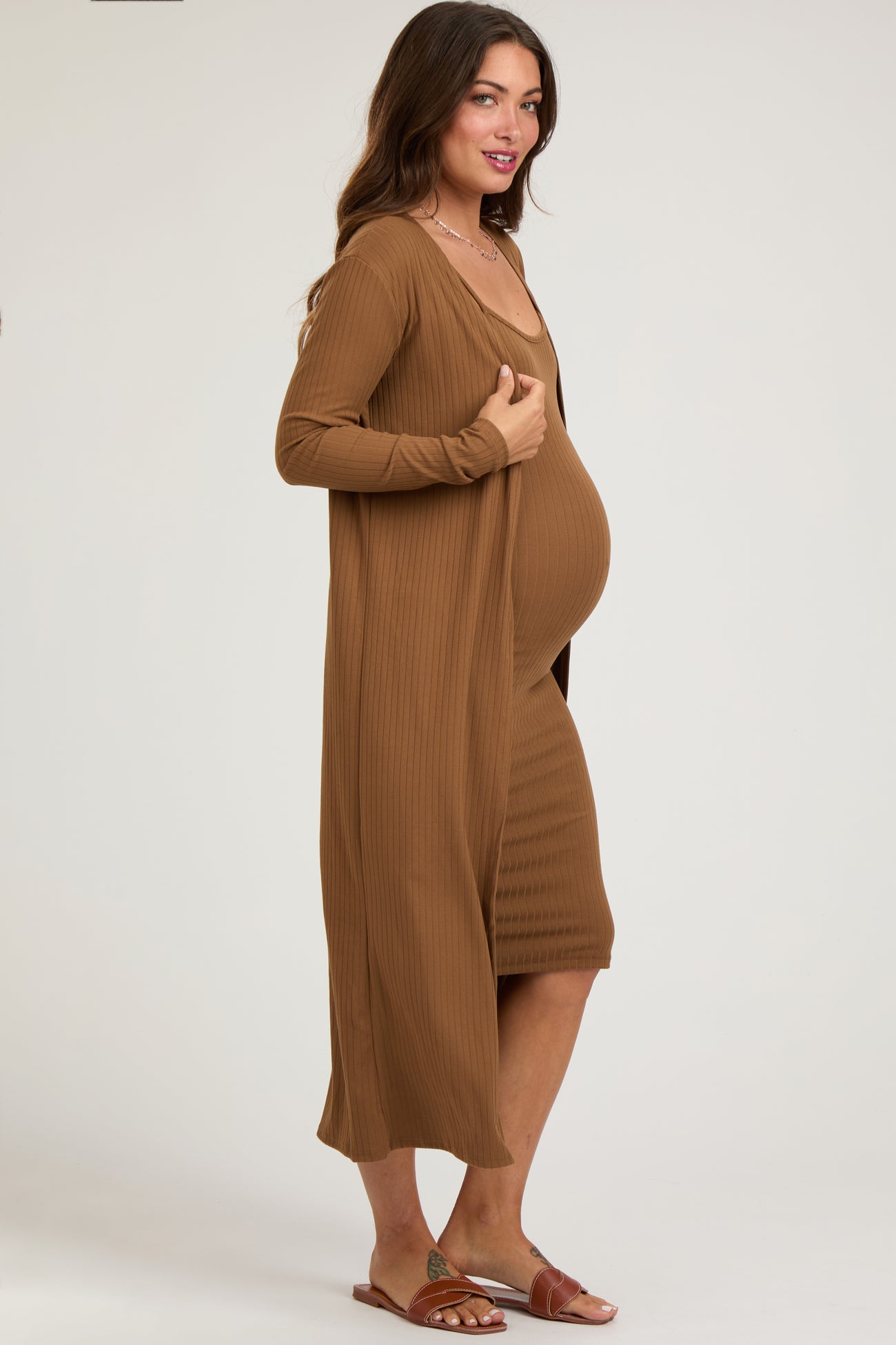 woman wearing a brown ribbed maternity dress with a matching long cardigan and showing her baby bump