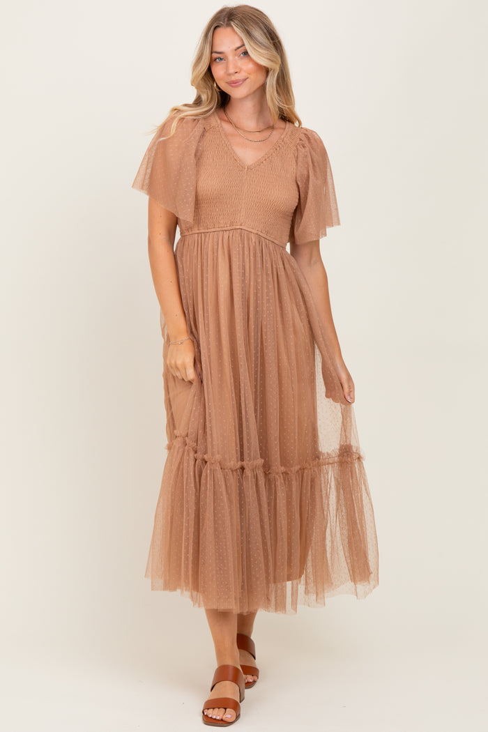 woman wearing a tan midi dress with puff sleeves and a tiered tulle skirt, styled with brown sandals