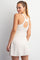woman wearing a light beige sleeveless dress with a racerback design and a subtle flared hemline