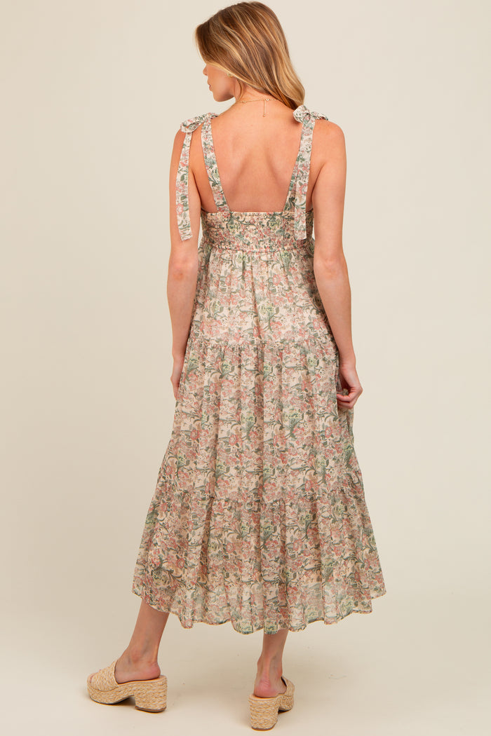 woman wearing a floral maternity maxi dress with tie shoulder straps and a smocked back, showing off her baby bump