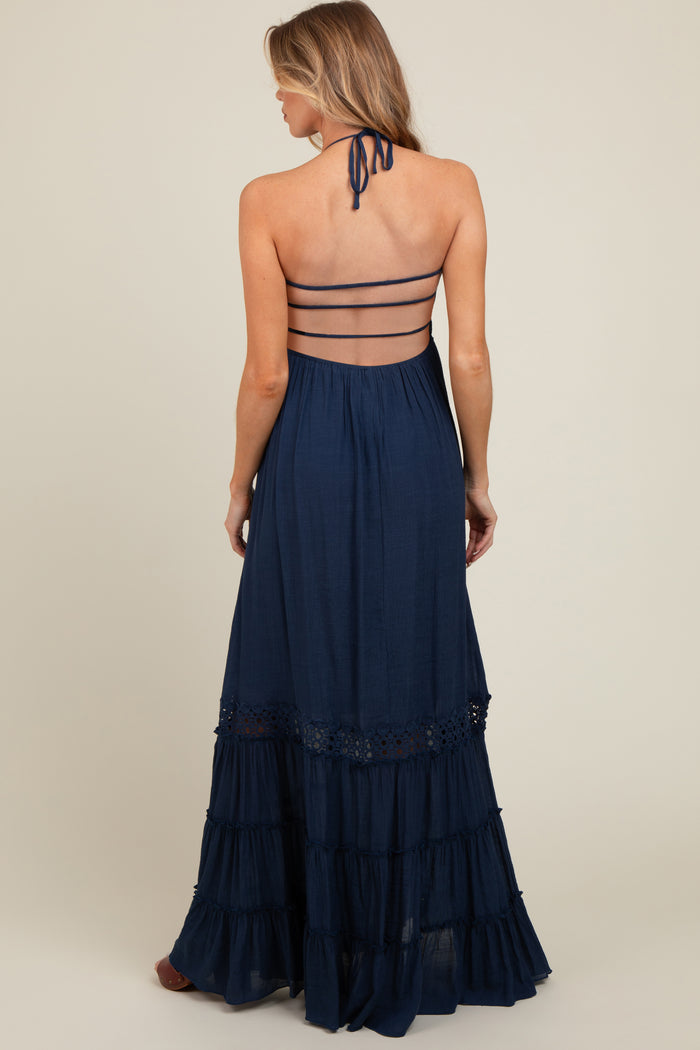 woman wearing a navy blue maternity maxi dress with a halter neck and tiered ruffles