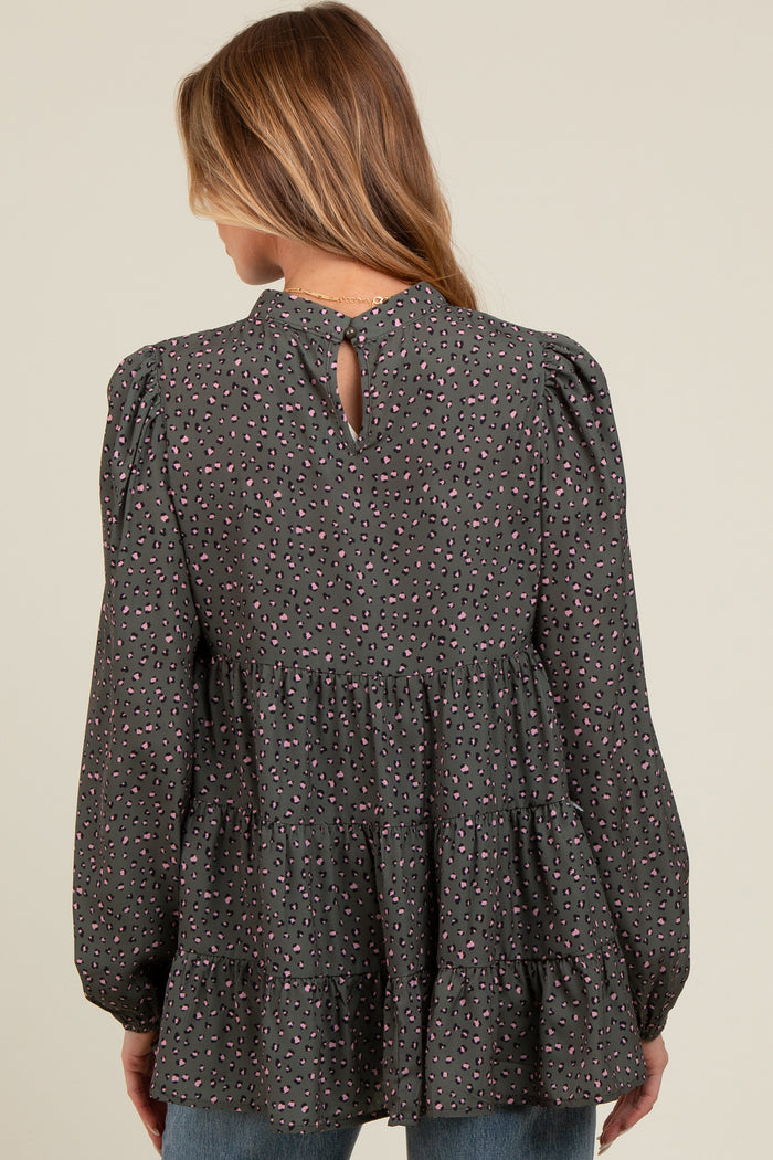 woman wearing a dark gray maternity top with a tiered design and colorful print, showing a keyhole detail at the back