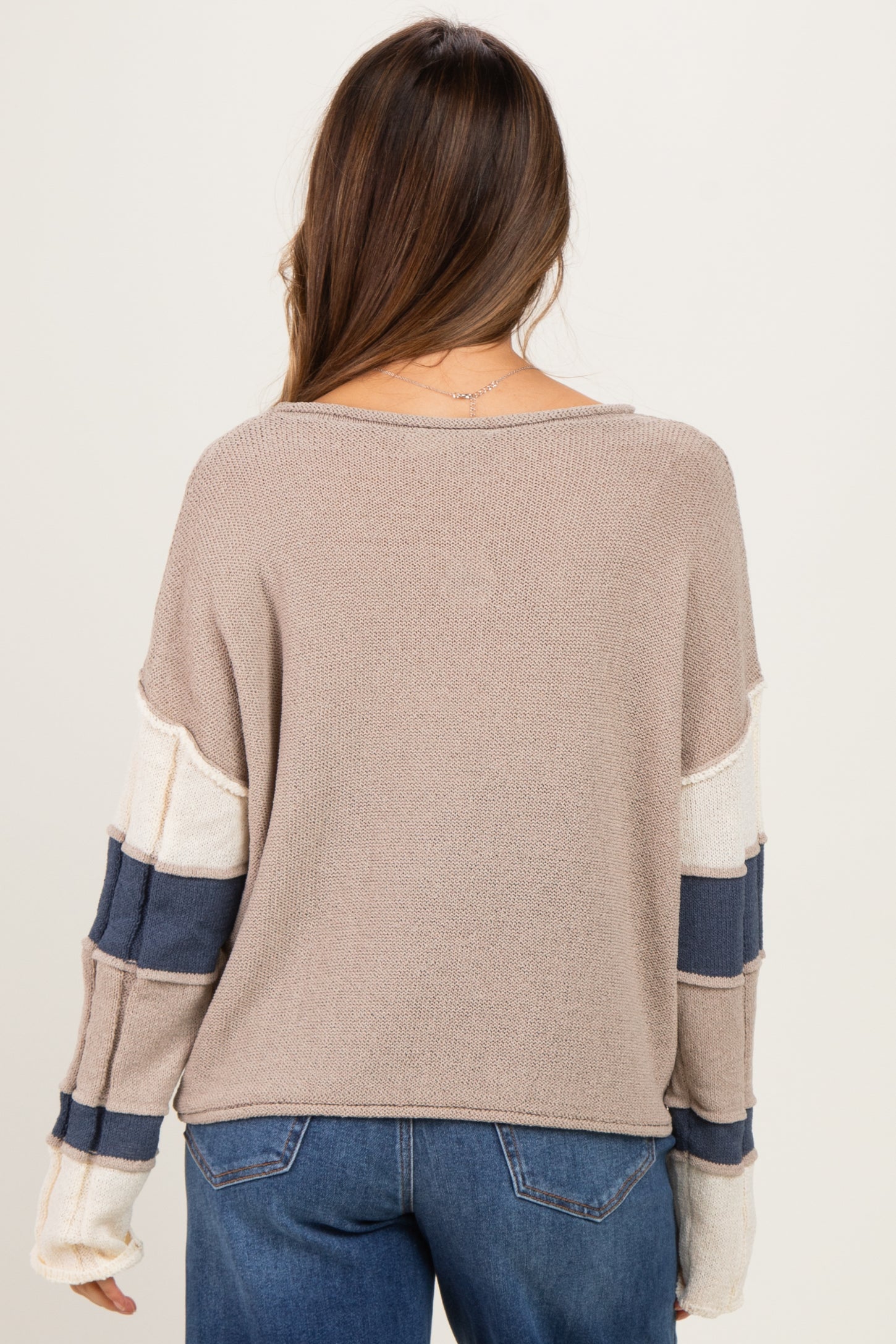 woman wearing a beige and white striped maternity sweater with navy details, showing the back view