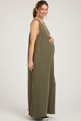 woman wearing a green striped maternity jumpsuit with buttons and holding her baby bump