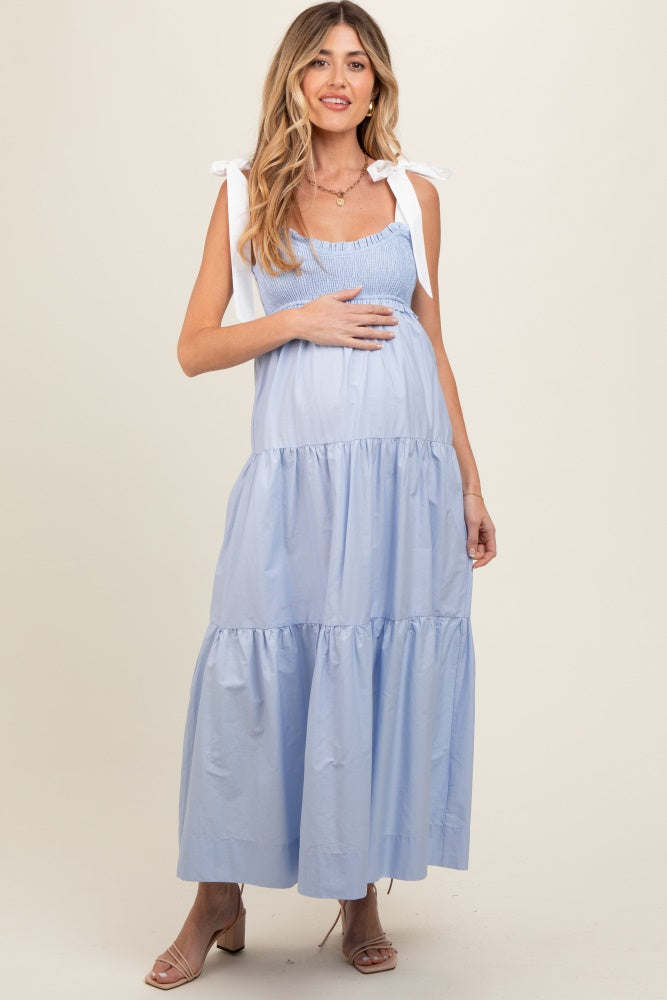 woman wearing a light blue smocked maternity dress with tie straps and a visible baby bump