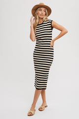 woman wearing a black and beige striped midi dress with cap sleeves and side slits, accessorized with a tan hat and sandals