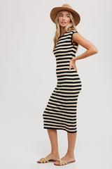 woman wearing a black and cream striped midi dress with short sleeves and a fitted silhouette, styled with a wide-brim hat and sandals