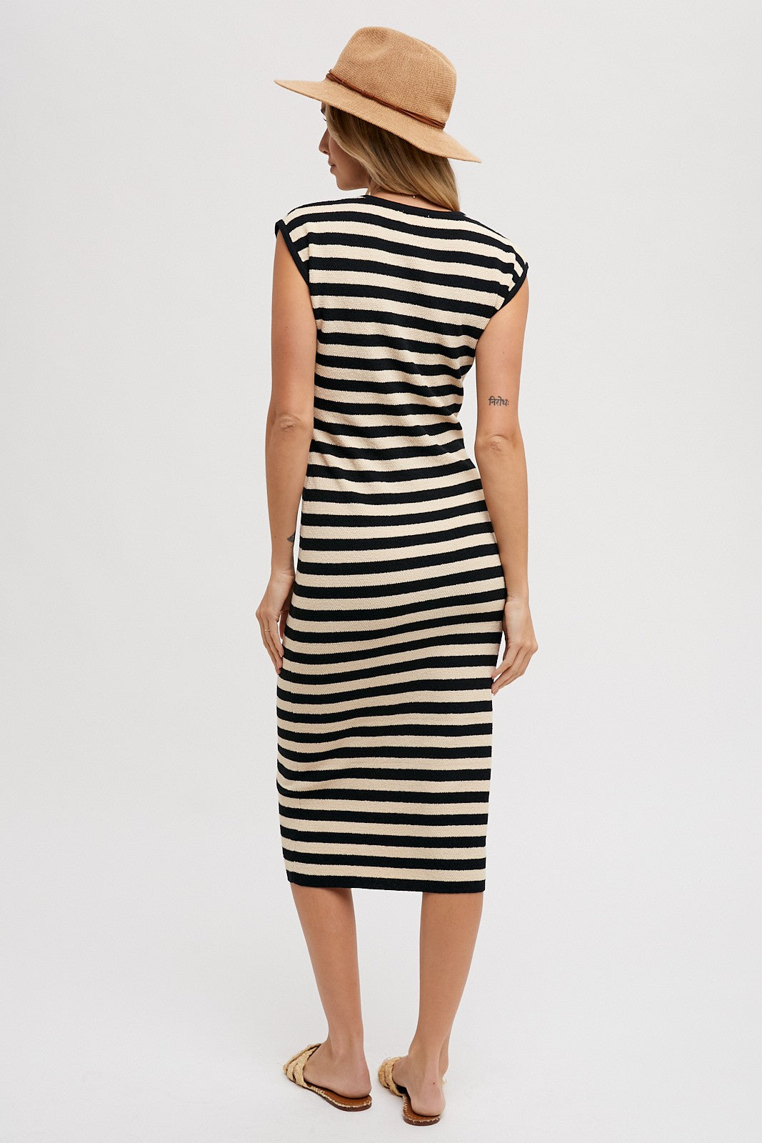 woman wearing a black and cream striped midi dress with cap sleeves and a straw hat