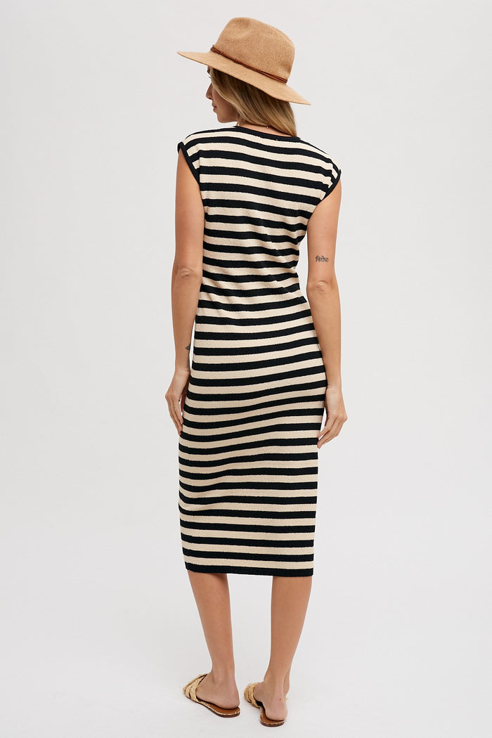 woman wearing a black and cream striped midi dress with cap sleeves and a straw hat