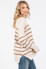 woman wearing a cream striped sweater with brown lines and relaxed fit, paired with blue jeans