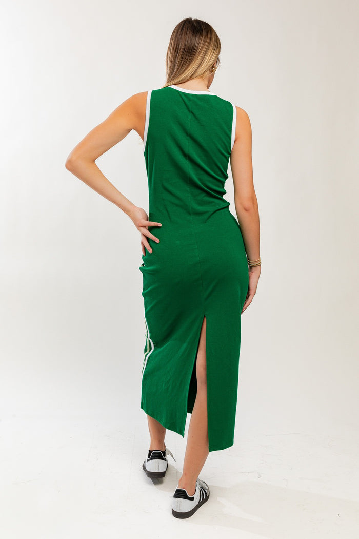 woman wearing a green midi dress with side slits and white accents, shown from the back