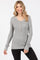 woman wearing a gray ribbed long sleeve henley top with buttons and fitted sleeves
