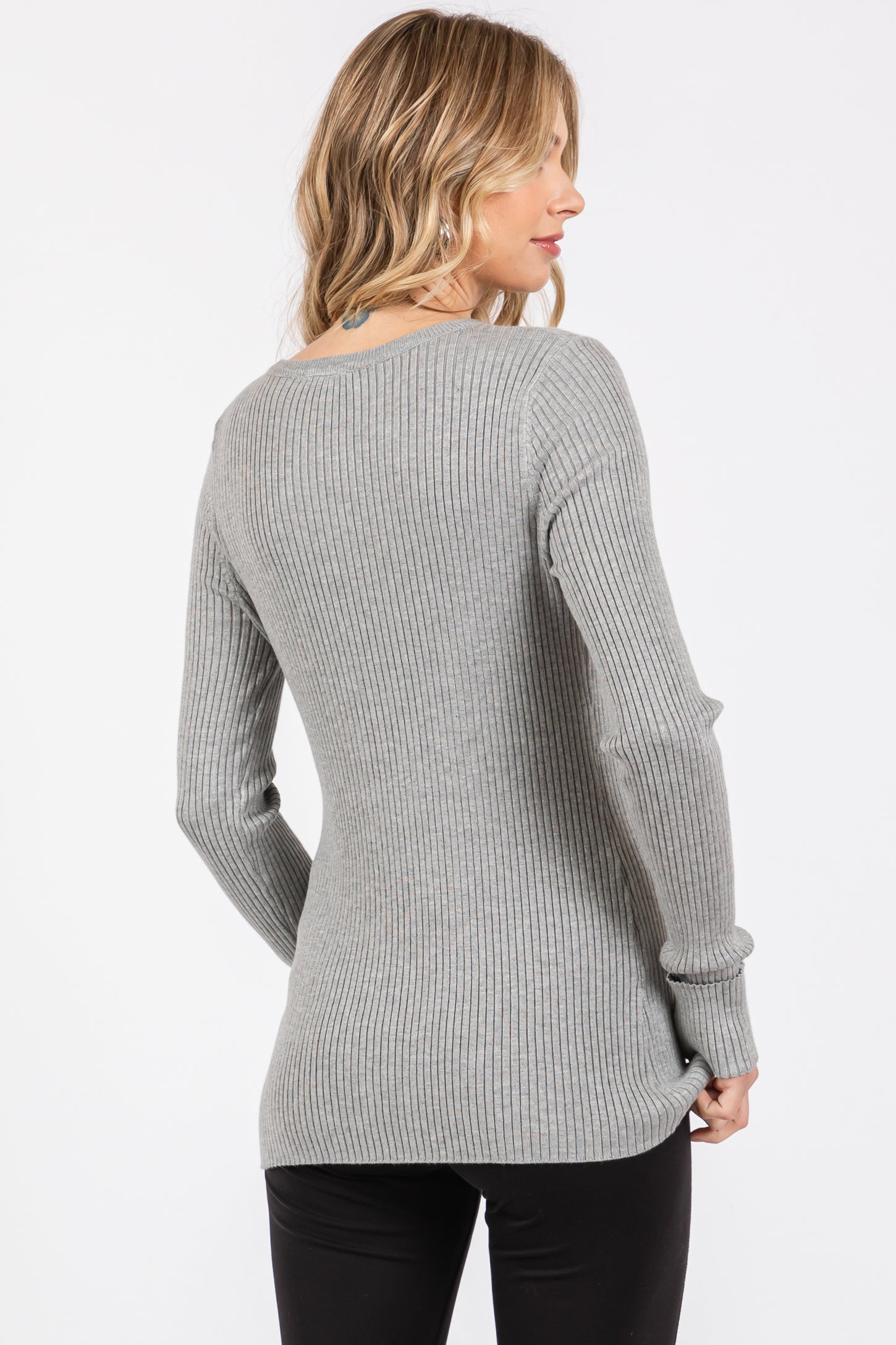 woman wearing a light gray ribbed long sleeve sweater, shown from the back, paired with black pants