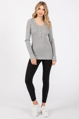 woman wearing a grey ribbed long sleeve henley top with buttons and black leggings, paired with white sneakers